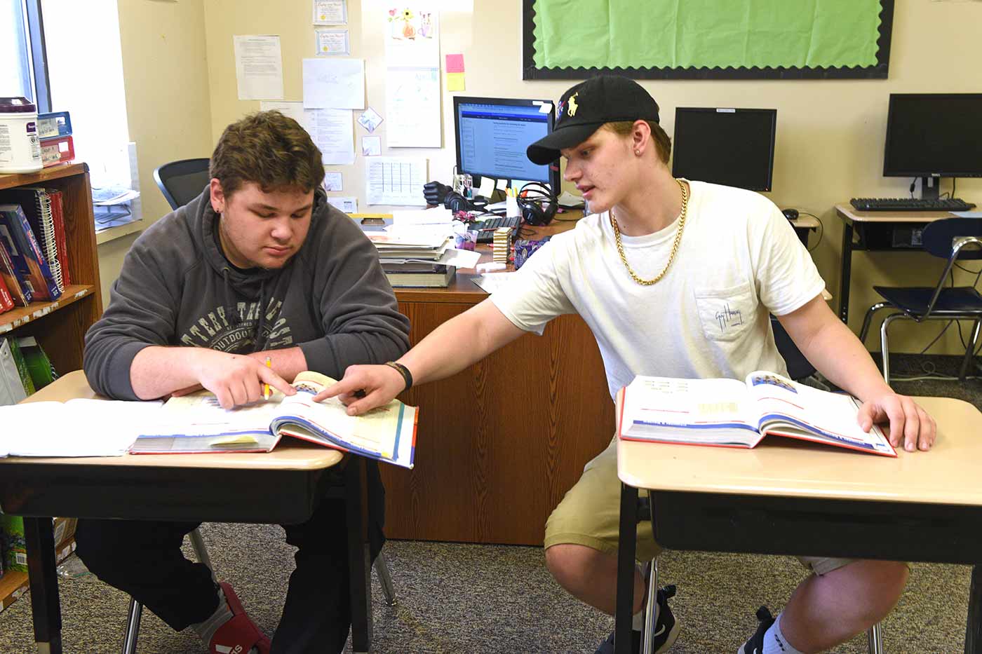 Two Natchaug students work together out of textbooks during class