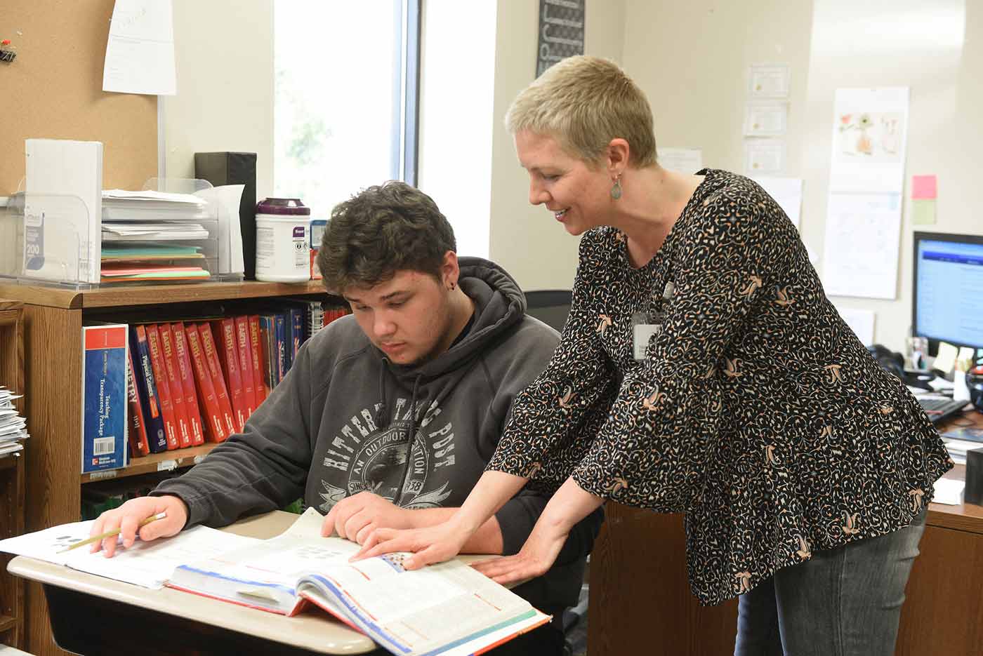 Teacher works one on one with Natchaug student while they learn from a textbook